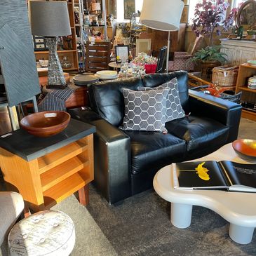 A real view inside Plain Jane's, with a black leather sofa, side tables, lamps and home decor