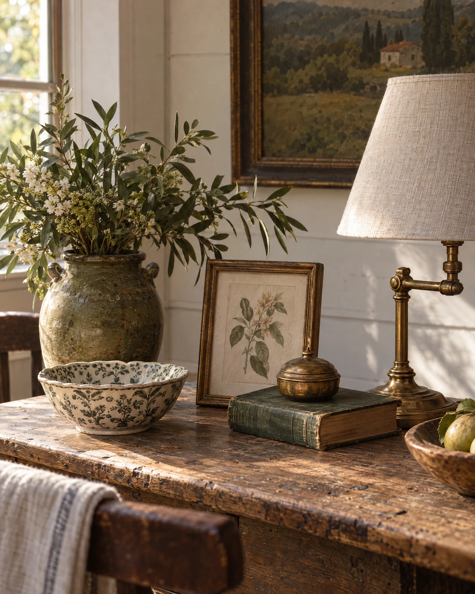 Illustrative still life of a vintage lamp, ceramic bowl, books and framed botanical art